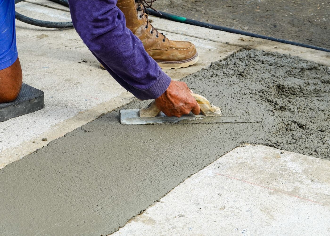 Worker smoothing out wet concrete flooring.