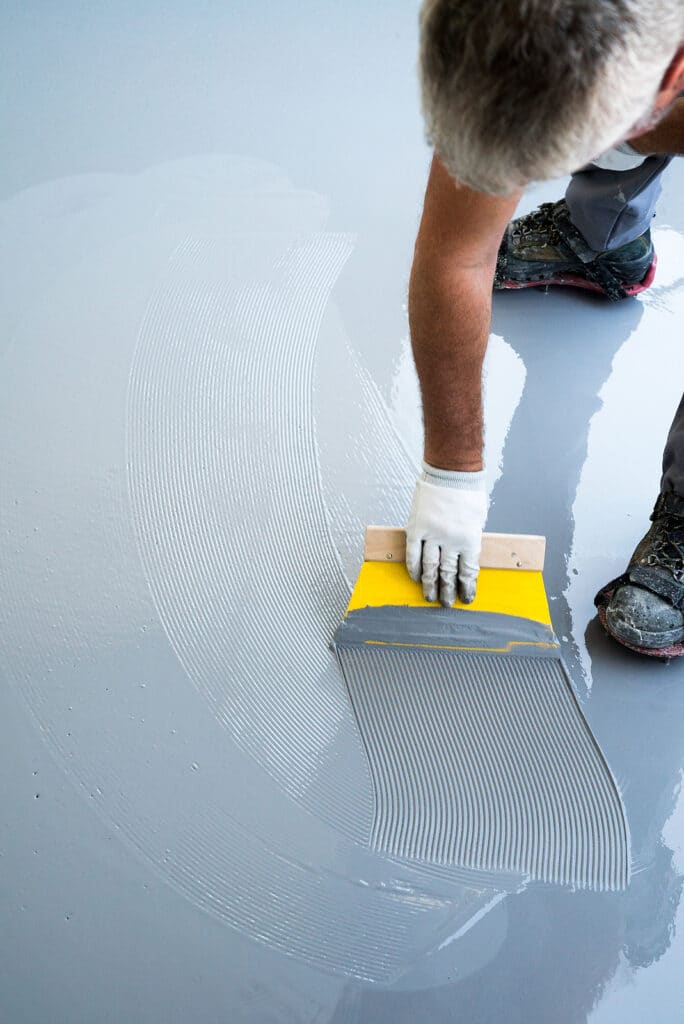 Construction worker spreading resin flooring