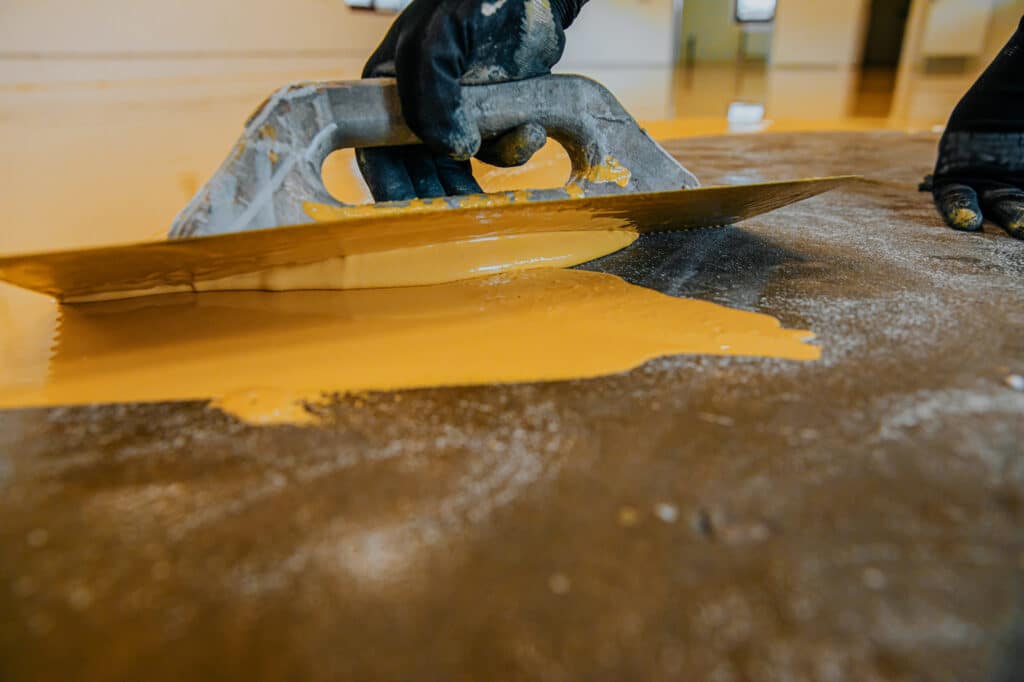 A Worker Coating A Floor With Self-levelling Epoxy Resin