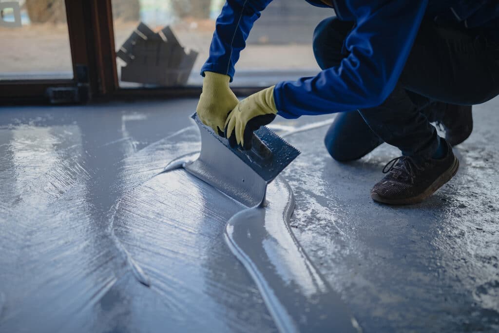 The Worker Applies Gray Epoxy Resin To The New Floor