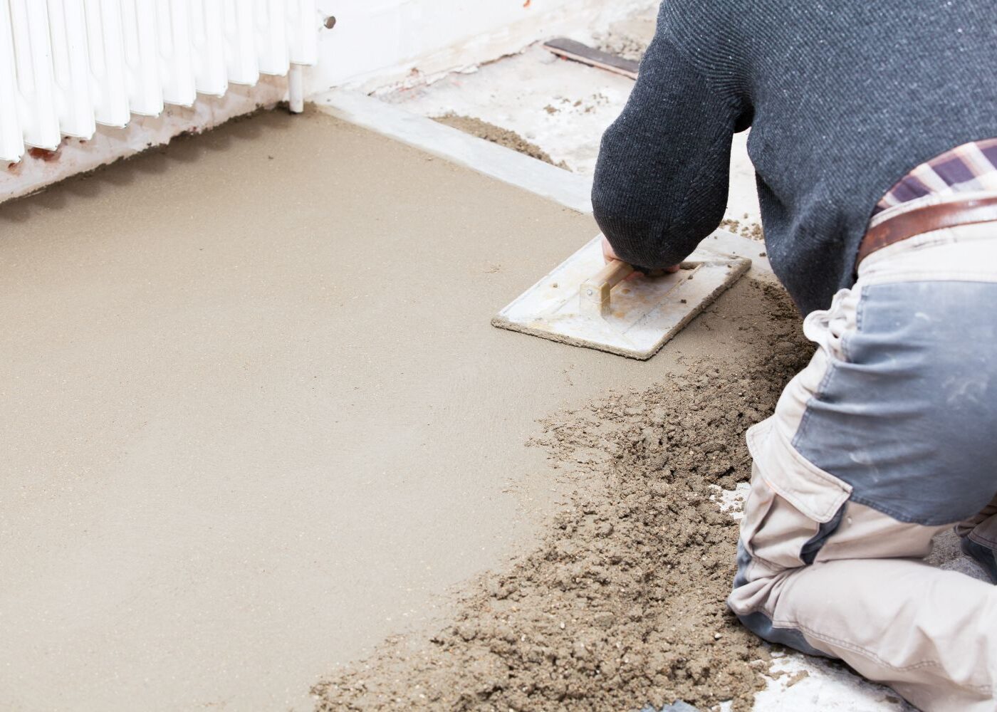 Man applying concrete screed to floor.