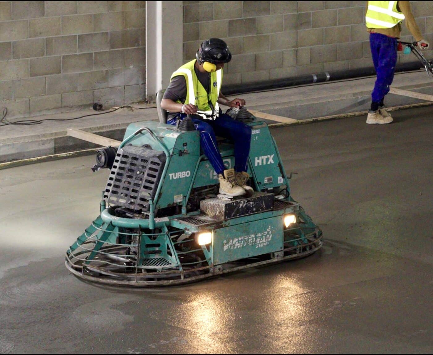 workman on ride on power float for concrete floor 