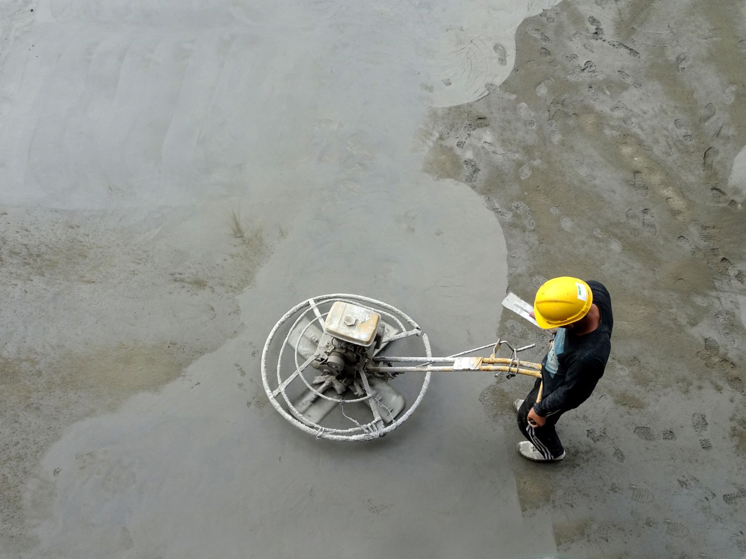 workman using power float on concrete floor
